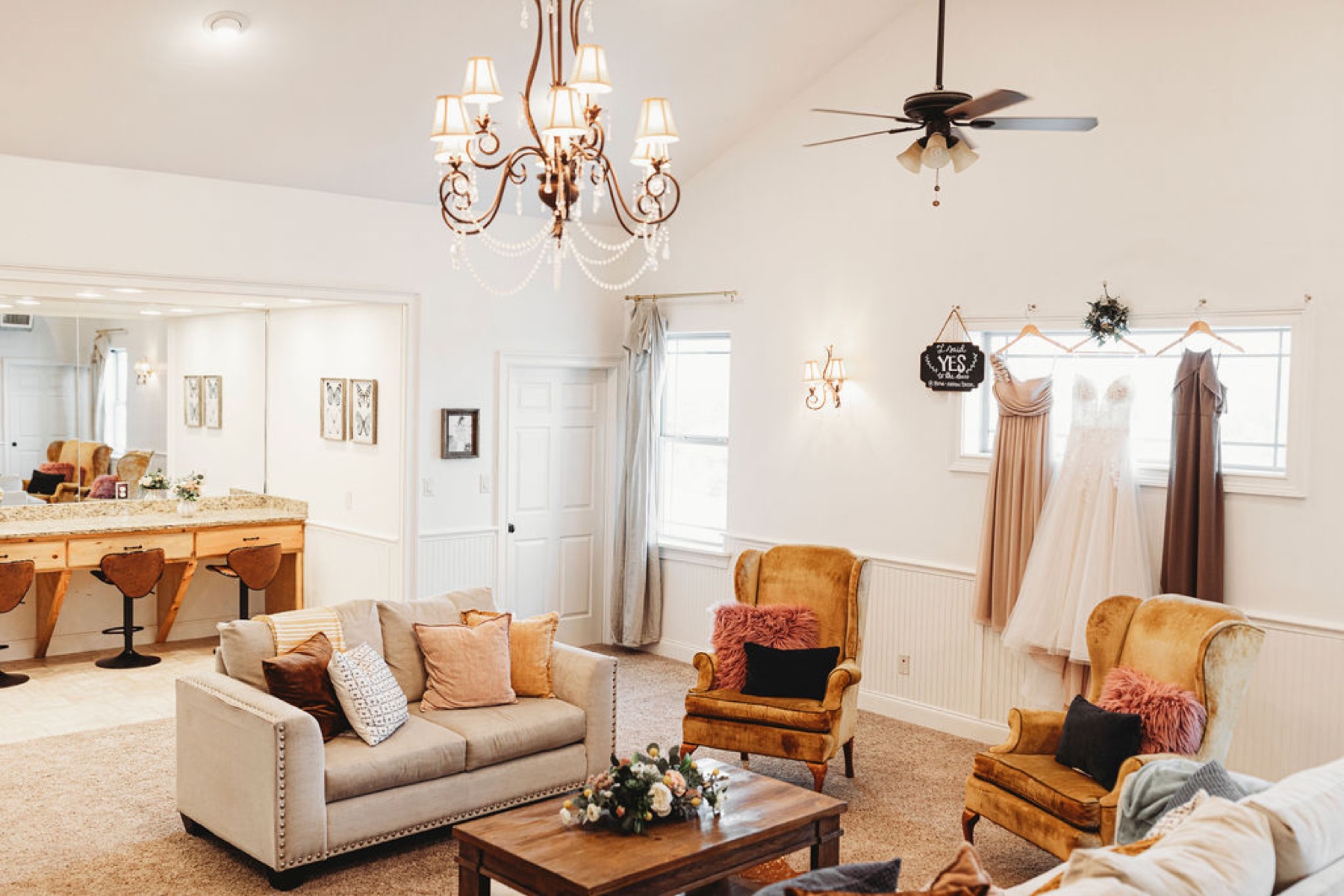 The bridal suite lounge at Diamond H3 Ranch with seating, a vanity, and the wedding dress hanging