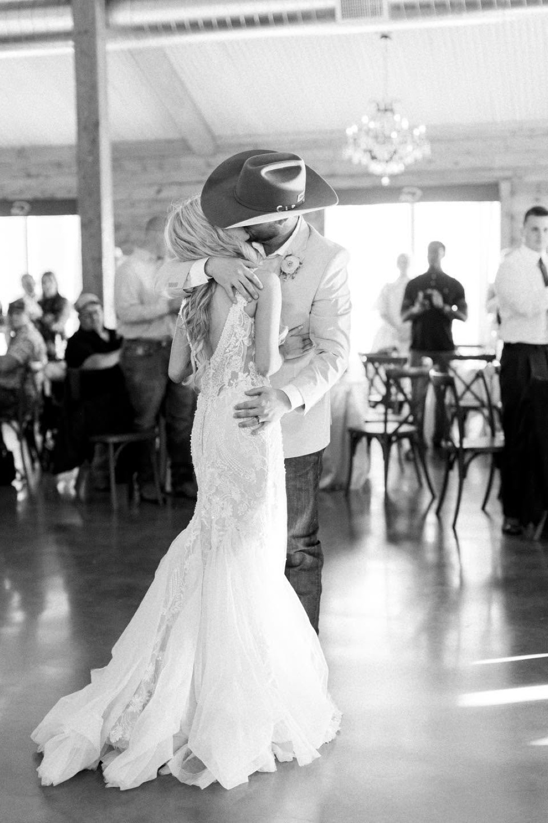 A couple's first-dance dip kiss on the dance floor in the cedar barn at Diamond H3 Ranch