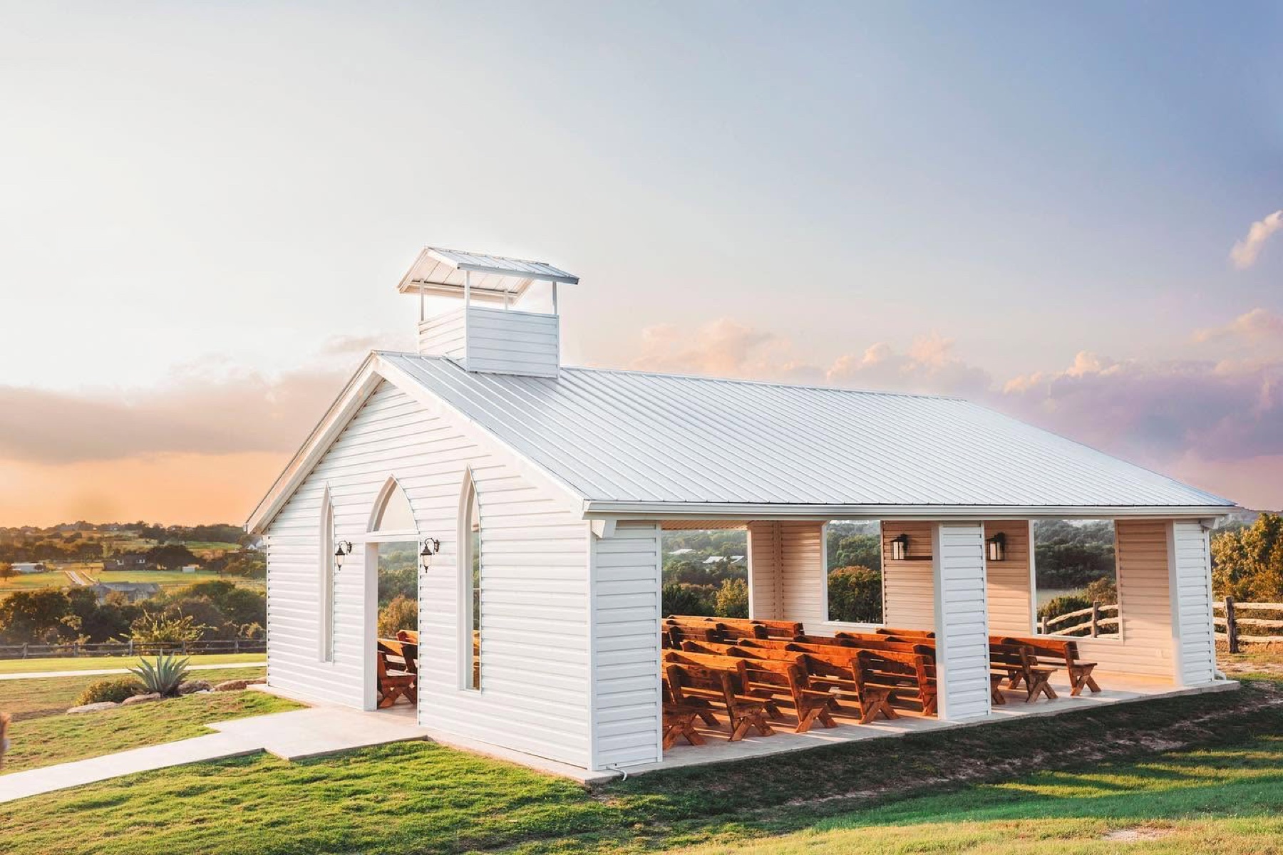 The white open-air chapel at Diamond H3 Ranch at sunset, overlooking the Texas hill country
